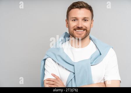 Ritratto in studio di un uomo caucasico barbato sorridente che guarda la fotocamera su sfondo grigio. Foto Stock