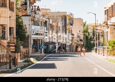 I turisti camminano lungo una nuova strada tra gli edifici abbandonati nella città fantasma di Varosha, Cipro del Nord, che riaprì al pubblico nel 2020 Foto Stock