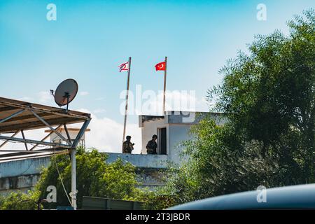 I soldati hanno una torre di guardia con bandiere turche e cipriote settentrionali che volano a un valico di frontiera a Nicosia settentrionale, Cipro Foto Stock
