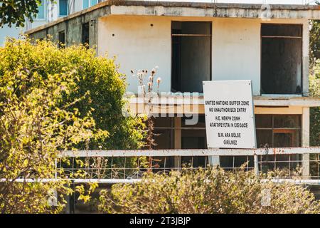 Un cartello recita "zona tampone delle Nazioni Unite, divieto di ingresso non autorizzato" davanti a un edificio abbandonato in un valico di frontiera sull'isola di Cipro Foto Stock