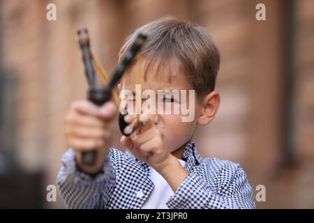 Bambino che gioca con la fionda all'aperto in città Foto Stock