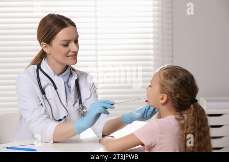 Medico che prende un campione di tampone alla gola dalla cavità orale della ragazza al chiuso Foto Stock