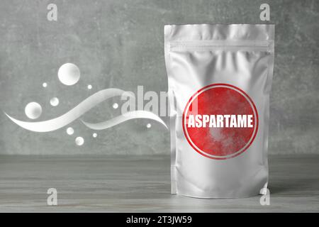 Aspartame. Confezione in foglio di alluminio con dolcificante artificiale su tavolo in legno grigio Foto Stock