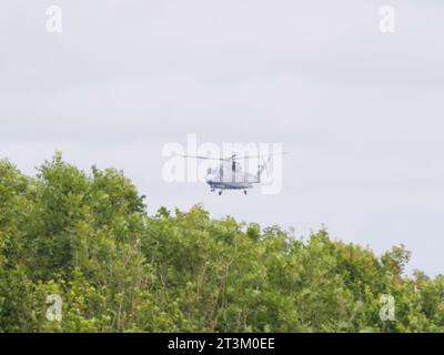 Un elicottero grigio della guardia costiera inglese vola contro un cielo grigio al largo della costa inglese vicino a Falmouth in Inghilterra Foto Stock