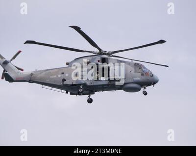 Un elicottero grigio della guardia costiera inglese sorvola con la porta aperta contro un cielo grigio al largo della costa inglese vicino a Falmouth in Inghilterra Foto Stock