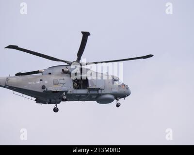 Un elicottero grigio della guardia costiera inglese sorvola con la porta aperta contro un cielo grigio al largo della costa inglese vicino a Falmouth in Inghilterra Foto Stock