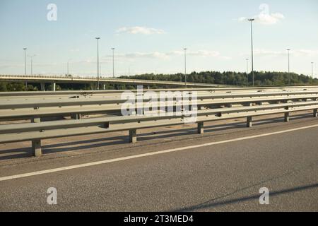 Paraurti lungo l'autostrada. Recinzione stradale. Architettura di trasporto sicura. Autostrada in estate. Foto Stock