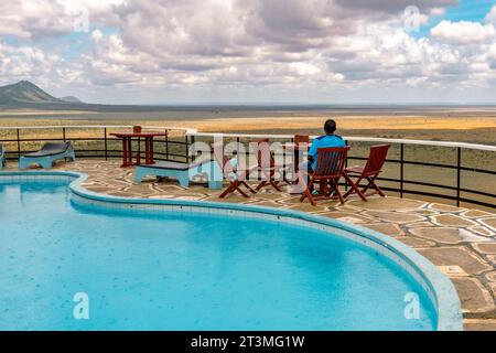 Un uomo vicino a una piscina in un punto panoramico in un Lodge al Tsavo East National Park, Kenya Foto Stock