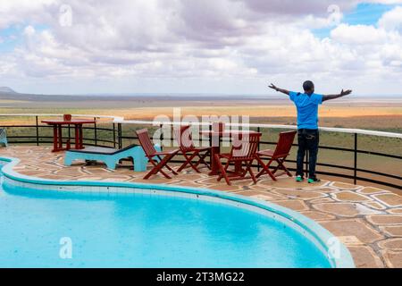 Un uomo vicino a una piscina in un punto panoramico in un Lodge al Tsavo East National Park, Kenya Foto Stock