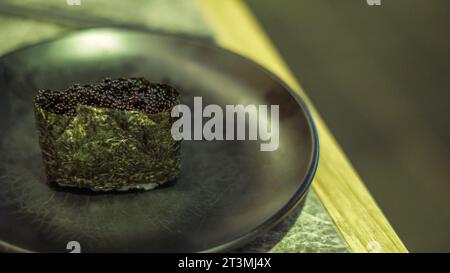 Il sushi è un tipico cibo giapponese contenente riso avvolto in alghe e ricoperto di caviale nero Foto Stock