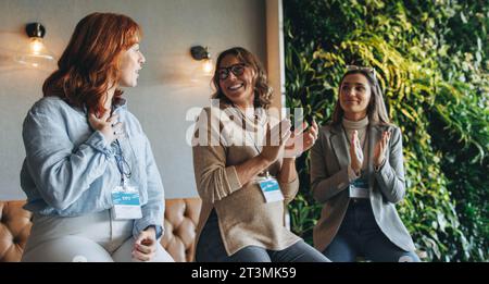 donne in affari e colleghi in un ufficio, che partecipano a una discussione di gruppo. Stanno applaudendo e sorridendo, mostrando il lavoro di squadra e un lavoro felice Foto Stock