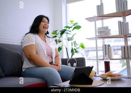 La donna Plus size sta mangiando la ciambella. Concetto di assistenza sanitaria e stile di vita. Foto Stock
