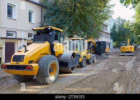 Attrezzature per la costruzione di strade: Escavatori, rulli per asfalto, bulldozer su una strada cittadina con il fondo stradale rimosso. Attrezzature per la riparazione e la posa Foto Stock