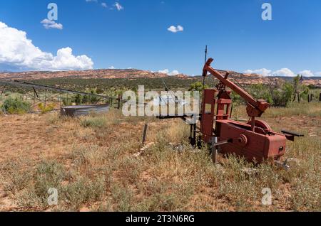 Una vecchia pompa meccanica su pozzi d'acqua in un ex ranch di bestiame nel sud-est dello Utah. Dietro c'è una pompa a vento o un mulino a vento collassati. Foto Stock