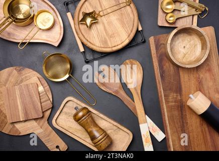 Vari utensili da cucina in legno su sfondo nero, vista dall'alto Foto Stock