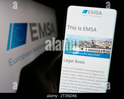 Persona che possiede il cellulare con la pagina web dell'Agenzia europea per la sicurezza marittima (EMSA) davanti al logo. Concentrarsi sul centro del display del telefono. Foto Stock
