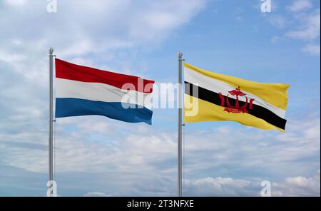 Le bandiere del Brunei e del Lussemburgo sventolano insieme su un cielo nuvoloso blu, concetto di due relazioni tra paesi Foto Stock