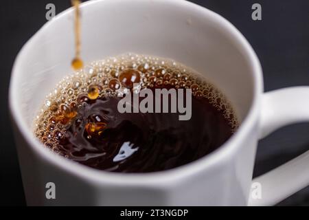 versare il caffè in un bicchiere in un espresso macro Foto Stock