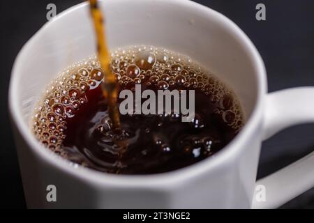versare il caffè in un bicchiere in un espresso macro Foto Stock
