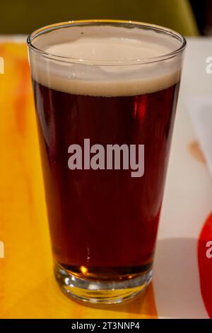 Una pinta di birra fresca britannica fredda e birra lager servita nel vecchio pub inglese d'epoca, sfondo scuro Foto Stock