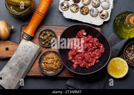 Cottura di una saporita tartare di manzo con cetriolini sottaceto e pane tostato. Spianatura piatta Foto Stock