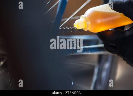 Primo piano del maschio che applica l'olio motore sulla vecchia bicicletta in officina Foto Stock