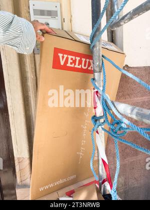 Parigi, Francia - 27 settembre 2023: La mano di un lavoratore recupera i rifiuti di cartone con il logo delle finestre Velux vicino all'ingresso di un edificio durante la ristrutturazione e la costruzione Foto Stock