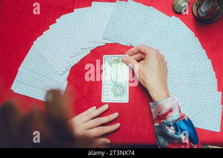 vista dall'alto irriconoscibile lettore di tarocchi di donna caucasica che tiene la carta con le mani sul tavolo, interpreta e fa lettura, collegandosi con le energie di Foto Stock