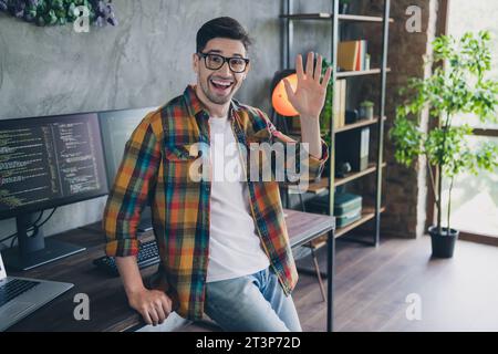 Foto dell'entusiasta project manager seduto al braccio della scrivania che sventola all'interno di un business center interno in un loft Foto Stock