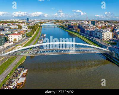 Cracovia, Polonia. Doppio ponte sospeso sotto un arco: Passerella pedonale e ponte in bicicletta sul fiume Vistola, chiamato kladka Bernatka. Popolare e turistico Foto Stock