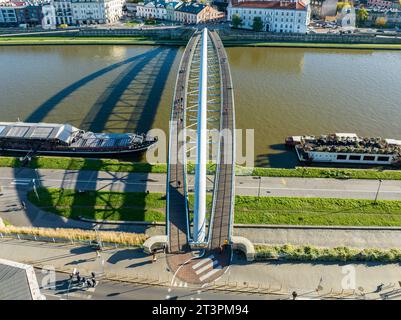 Cracovia, Polonia. Doppio ponte sospeso sotto un arco: Passerella pedonale e ponte in bicicletta sul fiume Vistola, chiamato kladka Bernatka. Popolare e turistico Foto Stock