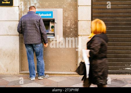 Scena di strada, uomo vicino al bancomat della banca di Sabadell. Madrid, Comunidad de Madrid, Spagna, Europa Foto Stock