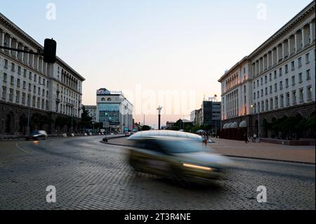 Auto veloci in Bulgaria. La statua di Sofia sorge maestosamente sullo sfondo, mentre i lucernari del complesso serdika brillano di fronte. Foto Stock
