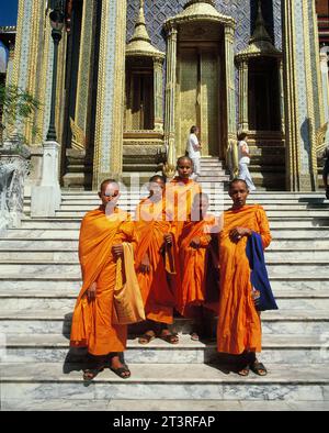 Thailandia. Bangkok. Wat Phra Kaew. Monaci buddisti in piedi sui gradini del tempio. Foto Stock
