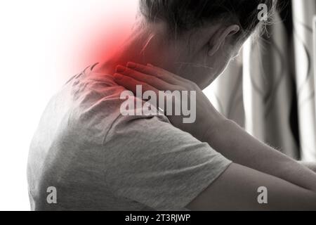Una ragazza tiene le mani dietro il collo a casa, mal di collo, dolore acuto al collo Foto Stock