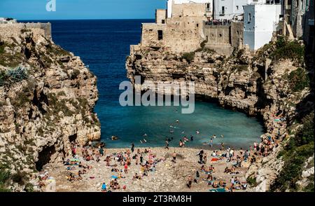 Gente che si gode la spiaggia di Cala Ponte a Polignano a Mare, IIaly, in una domenica soleggiata pomeriggio di ottobre. Foto Stock