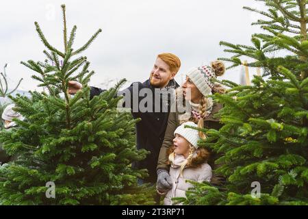 Famiglia Acquisto di albero di Natale sul mercato tenendo it home Foto Stock
