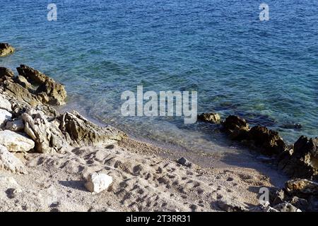 Costa con ciottoli bianchi e rocce bianche accanto al mare blu ondulato in una natura incontaminata Foto Stock