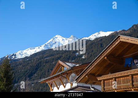 Un tipico tetto in legno in stile alpino con montagne innevate sullo sfondo a Neustift im Stubaital, Austria Foto Stock