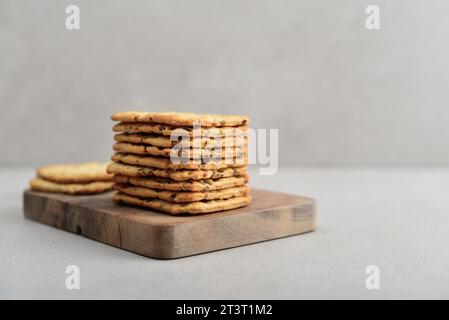 Biscotti croccanti a grana multipla con lino e semi di sesamo su tagliere di legno su sfondo chiaro Foto Stock