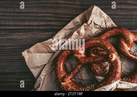 Due morbidi pretzel con semi di sesamo su sfondo di legno, vista dall'alto Foto Stock