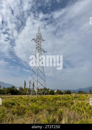Tralicci aerei, tralicci ad alta tensione in prato con montagne sullo sfondo nelle giornate di sole estive, vicino a Oricum, Albania Foto Stock