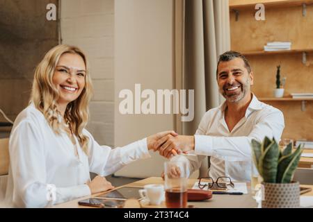 Due aziende di mezza età, uomini e donne, leader delle aziende che si stringono la mano dopo aver fatto un accordo sul nuovo progetto in arrivo Foto Stock