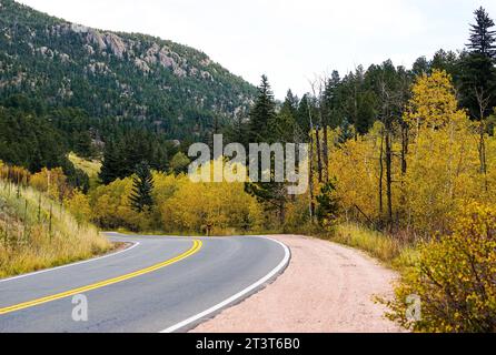 Una strada tortuosa attraversa il Golden Gate Canyon State Park in Colorado, con alberi di Aspen che cambiano lungo la strada e pini in cima alle montagne Foto Stock