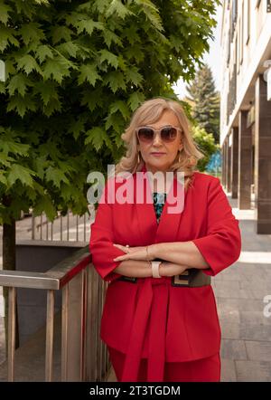Ritratto in posa donna d'affari, donna senatrice matura all'aperto in estate, città, elegante donna anziana sicura di sé negli anni '60 indossa gli occhiali da sole Foto Stock