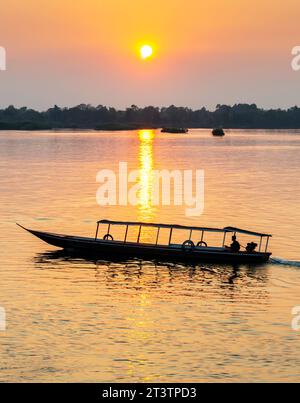 Sagome di due figure umane in kayak, che attraversano le calme e tranquille acque del Mekong, attraverso raggi di luce dorata riflessa sull'acqua, Foto Stock