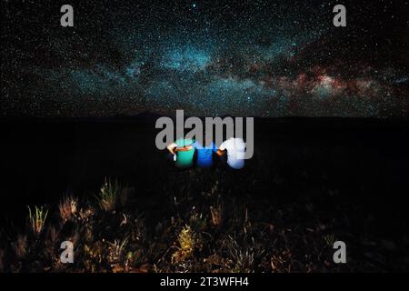 Tre amici seduti in un prato che guarda la via Lattea, foto scattata il 06/25/2023 sulle colline toscane Firenze Italia Foto Stock