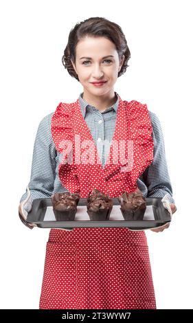 Sorridente donna vintage tenendo un vassoio da forno con cioccolato fatta in casa muffin Foto Stock