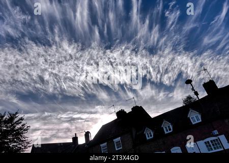 Nuvole di Cirrus note anche come code di mares, con case sotto. Inghilterra Regno Unito Foto Stock