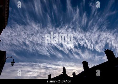 Nuvole di Cirrus note anche come code di mares, con case sotto. Inghilterra Regno Unito Foto Stock
